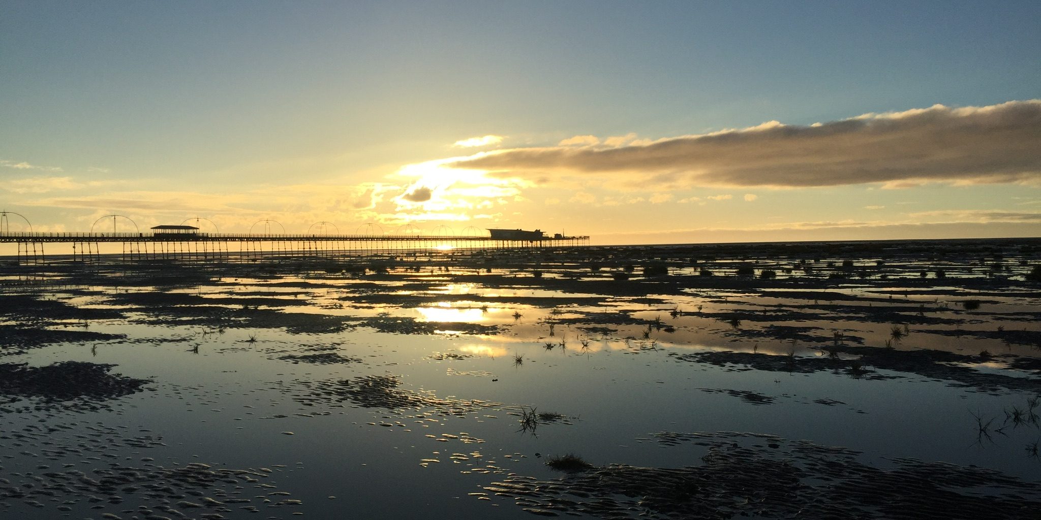 Sun going down over Southport Pier and Beach .